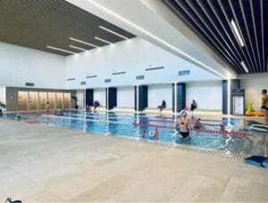 Antrenori care coordonează exercițiile copiilor la bazin