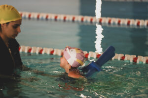 Antrenoare care asistă un copil în timpul unei ședințe de înot