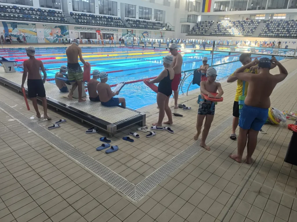 Grup de copii și instructori lângă scara de acces în bazin