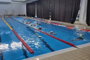Antrenori în apă alături de copii care exersează cu materiale plutitoare